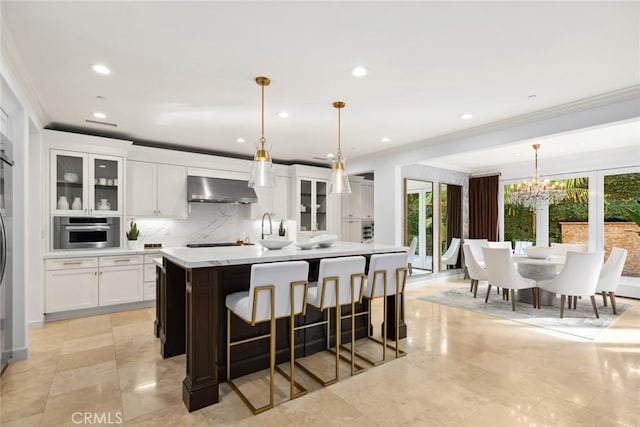 kitchen featuring pendant lighting, oven, a center island with sink, and extractor fan