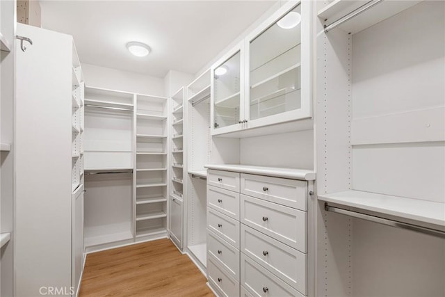 walk in closet with light hardwood / wood-style flooring