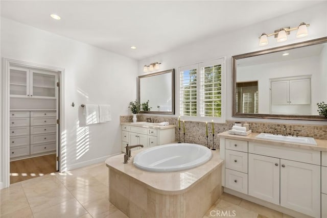 bathroom featuring a relaxing tiled tub, tile patterned floors, and vanity