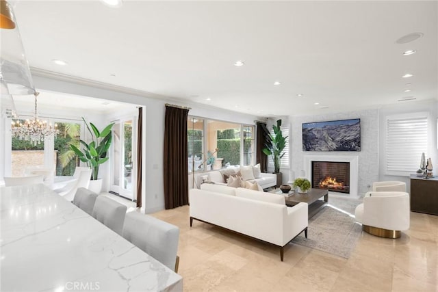 living room with a high end fireplace, ornamental molding, and a notable chandelier