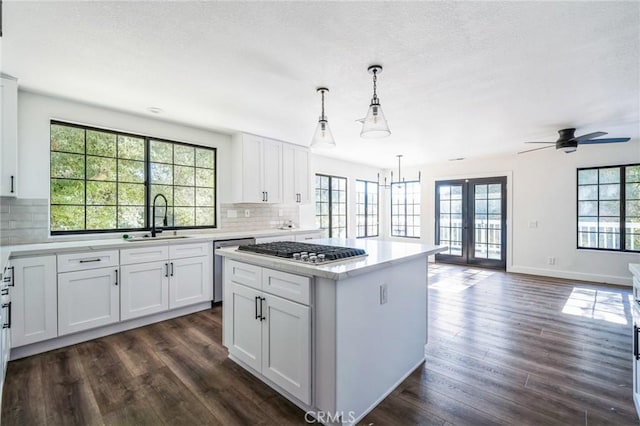 kitchen with sink, white cabinets, hanging light fixtures, a center island, and dark wood-type flooring