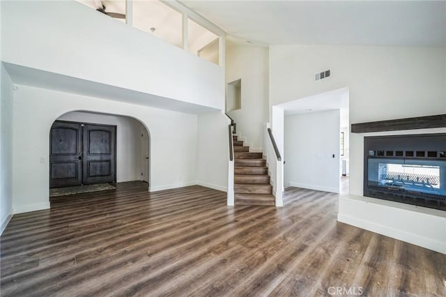 unfurnished living room with a multi sided fireplace, dark hardwood / wood-style floors, and high vaulted ceiling