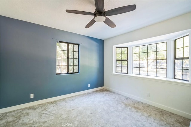 empty room featuring a healthy amount of sunlight, light colored carpet, and ceiling fan