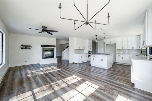 kitchen with sink, white cabinetry, backsplash, hanging light fixtures, and a kitchen island