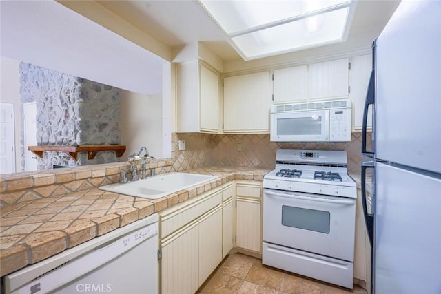 kitchen featuring tasteful backsplash, white appliances, tile counters, and sink