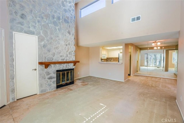 unfurnished living room featuring a high ceiling, light colored carpet, and a fireplace