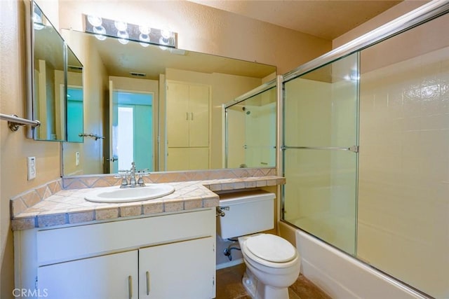 full bathroom with vanity, toilet, and combined bath / shower with glass door