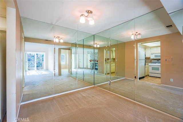 unfurnished bedroom featuring stainless steel refrigerator and light carpet