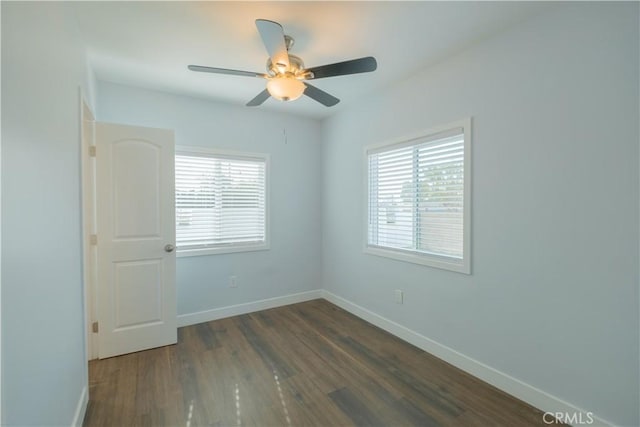 empty room featuring dark wood-type flooring, a wealth of natural light, and ceiling fan