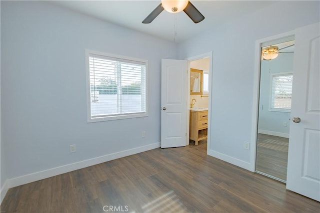 unfurnished bedroom featuring ceiling fan, sink, ensuite bath, and dark wood-type flooring