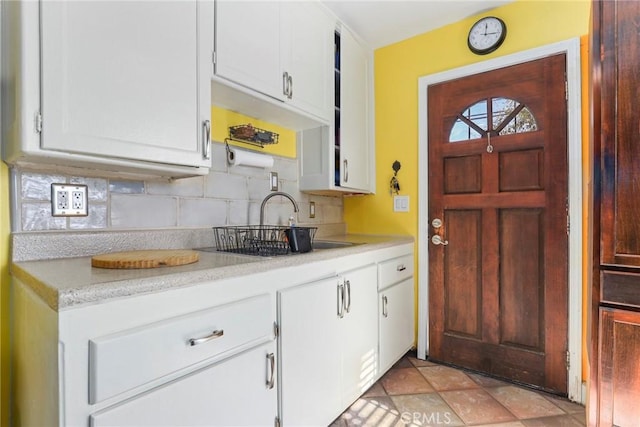 kitchen with light tile patterned flooring, sink, white cabinetry, and tasteful backsplash