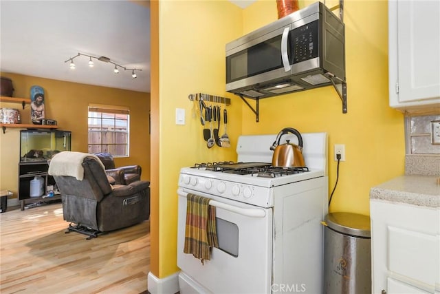 kitchen with light wood-type flooring, backsplash, white cabinets, and white gas range oven