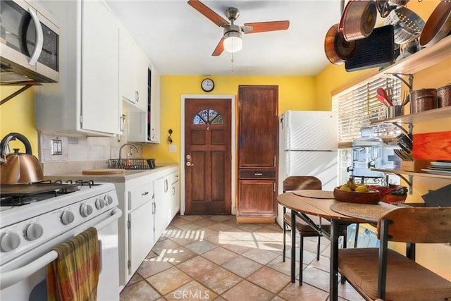 kitchen featuring backsplash, sink, white appliances, and white cabinetry