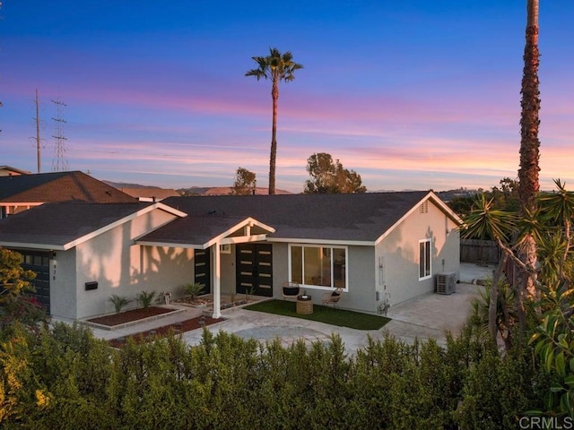 back house at dusk featuring a patio area and central AC