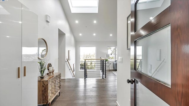 foyer featuring high vaulted ceiling, a skylight, and dark wood-type flooring