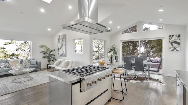 kitchen featuring white cabinets, light hardwood / wood-style floors, island range hood, vaulted ceiling, and a breakfast bar area