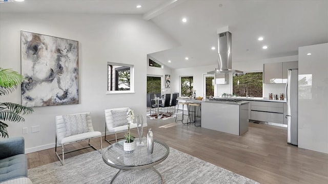 living room featuring light wood-type flooring, high vaulted ceiling, and beamed ceiling