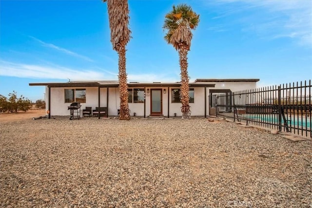 back of property with a patio area and a fenced in pool