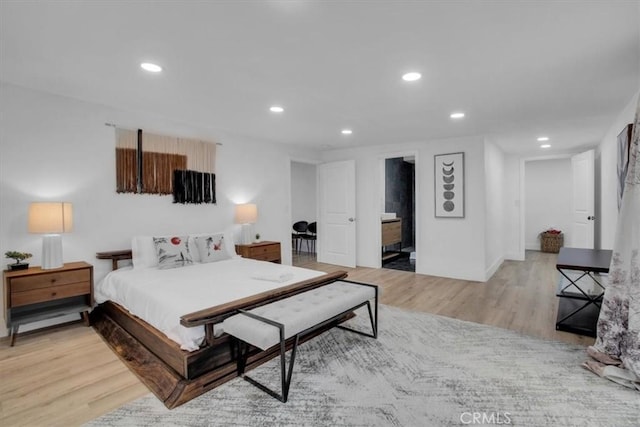 bedroom featuring connected bathroom and light wood-type flooring