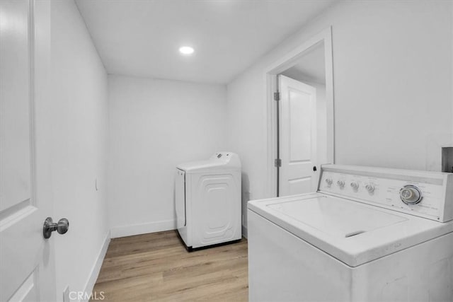 clothes washing area with washer / dryer and light hardwood / wood-style flooring