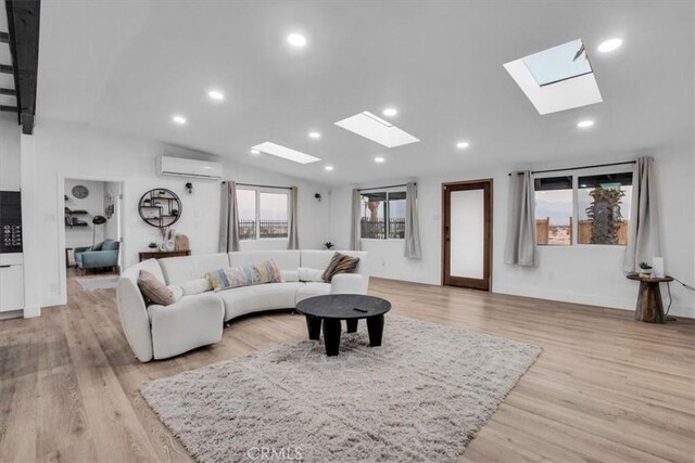 living room with a healthy amount of sunlight, a wall mounted AC, vaulted ceiling, and light hardwood / wood-style flooring