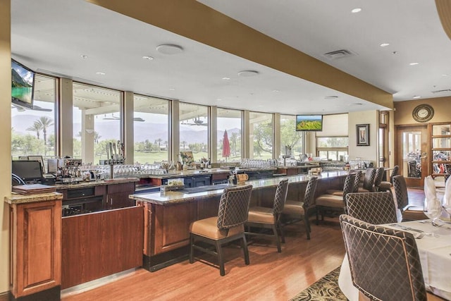 bar with light hardwood / wood-style floors and dark stone counters