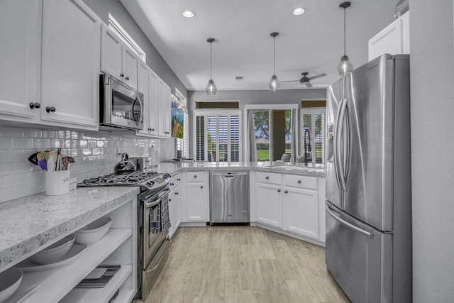 kitchen featuring appliances with stainless steel finishes, white cabinetry, and hanging light fixtures