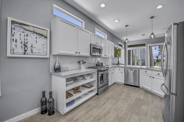 kitchen featuring white cabinets, stainless steel appliances, backsplash, hanging light fixtures, and light stone counters