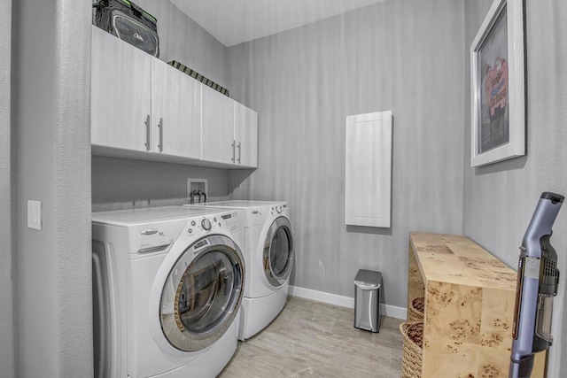 laundry room featuring cabinets, light hardwood / wood-style flooring, and washing machine and clothes dryer