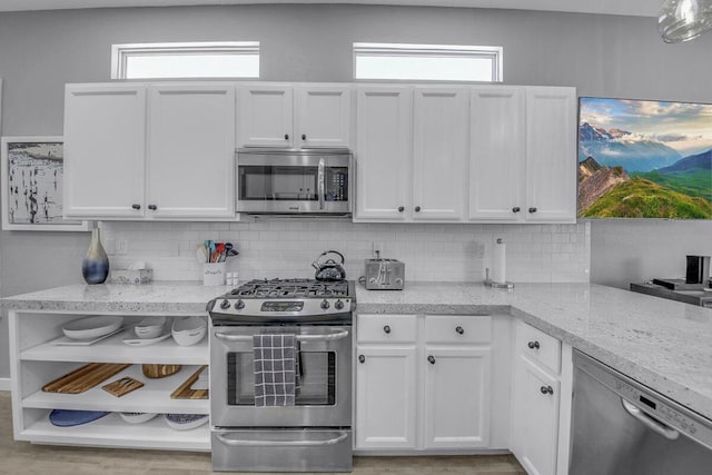 kitchen featuring light stone countertops, white cabinets, appliances with stainless steel finishes, and tasteful backsplash