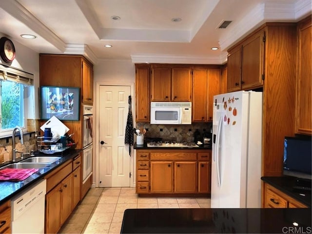 kitchen with a raised ceiling, decorative backsplash, sink, white appliances, and crown molding