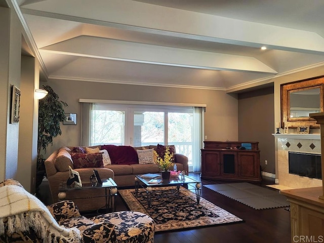 living room with lofted ceiling, a tiled fireplace, crown molding, and hardwood / wood-style flooring