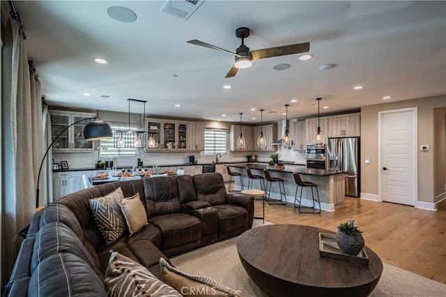 living room with ceiling fan, light wood-type flooring, and sink