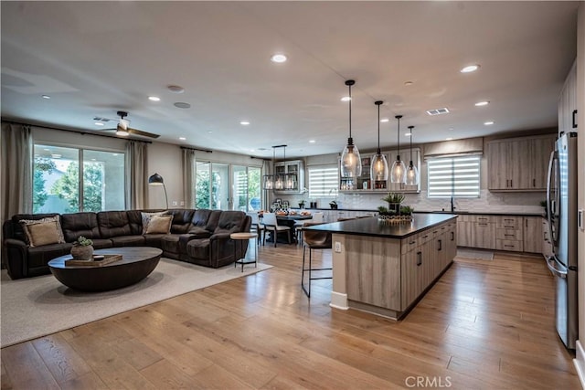 kitchen with decorative light fixtures, light wood-type flooring, backsplash, and a kitchen island