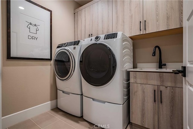 laundry room with sink, light tile patterned flooring, washing machine and clothes dryer, and cabinets