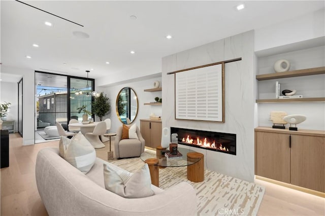 living room with a fireplace, a wall of windows, and light hardwood / wood-style flooring