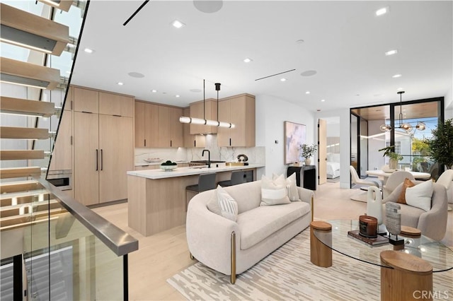 living room featuring an inviting chandelier, sink, and light wood-type flooring