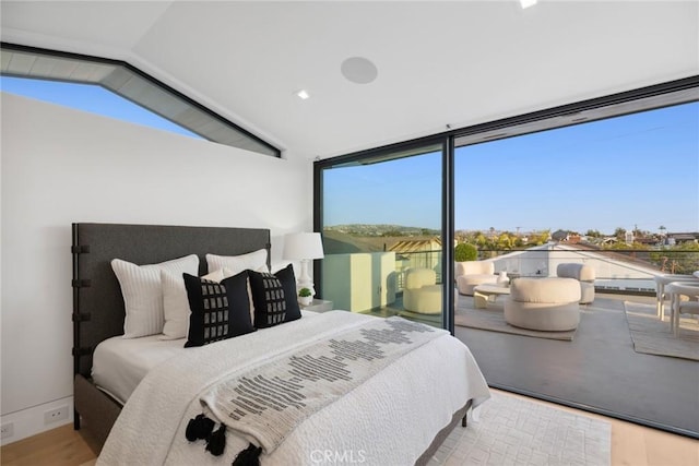 bedroom featuring lofted ceiling, floor to ceiling windows, and light wood-type flooring