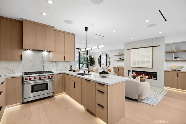 kitchen with sink, designer range, light brown cabinetry, kitchen peninsula, and light wood-type flooring