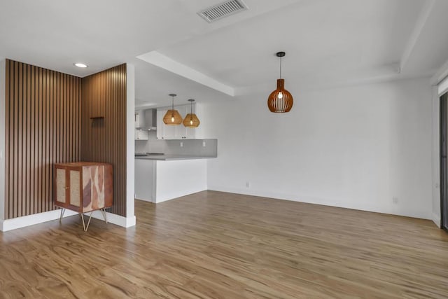 unfurnished living room featuring a raised ceiling and light hardwood / wood-style flooring