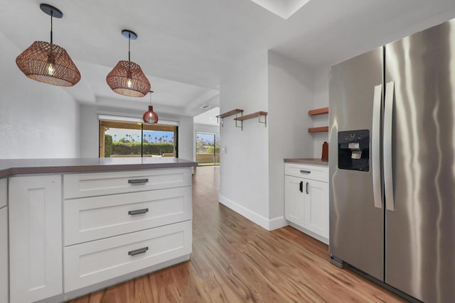 kitchen with white cabinetry, hanging light fixtures, stainless steel fridge with ice dispenser, and light wood-type flooring