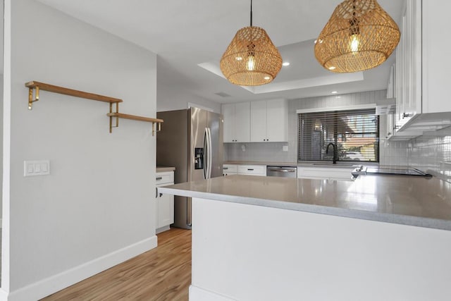 kitchen with decorative light fixtures, white cabinets, kitchen peninsula, and stainless steel appliances