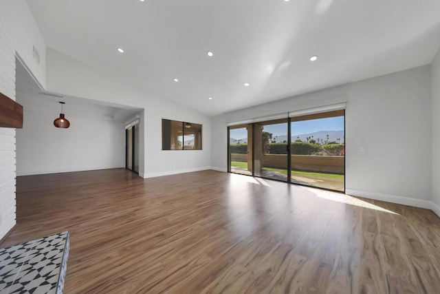 unfurnished living room with hardwood / wood-style flooring, a brick fireplace, and lofted ceiling