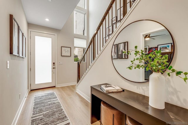 entrance foyer with a high ceiling, plenty of natural light, ceiling fan, and light wood-type flooring