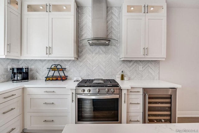 kitchen featuring white cabinetry, beverage cooler, stainless steel range with gas stovetop, and wall chimney exhaust hood