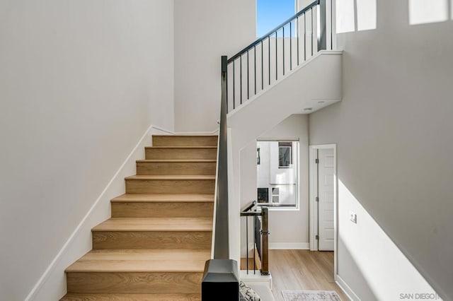 stairs featuring hardwood / wood-style floors and a high ceiling