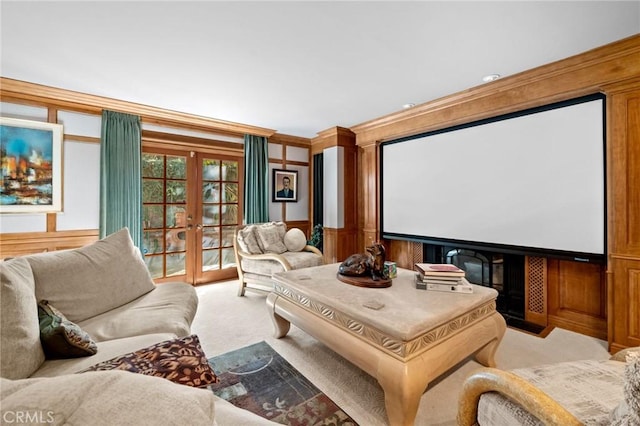 home theater with light carpet, wood walls, ornamental molding, and french doors