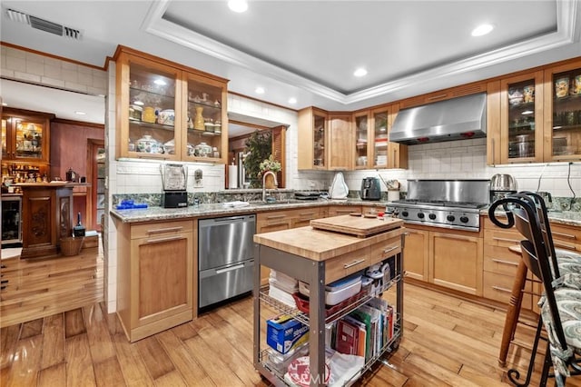 kitchen with range hood, light hardwood / wood-style flooring, and light stone countertops