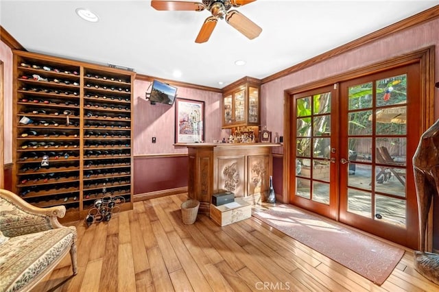 wine cellar with ceiling fan, light hardwood / wood-style flooring, crown molding, and french doors