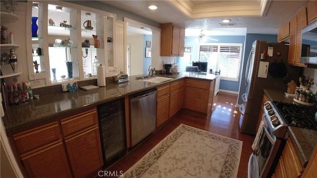 kitchen with sink, ornamental molding, a tray ceiling, kitchen peninsula, and stainless steel appliances